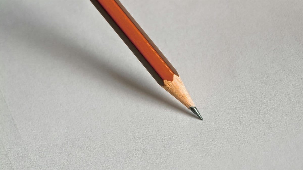 Detailed close-up of a wooden pencil resting on white paper, perfect for educational themes.