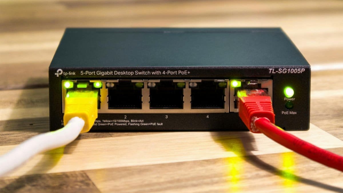 Close-up of a TP-Link Ethernet switch with yellow, red, and white cables connected.