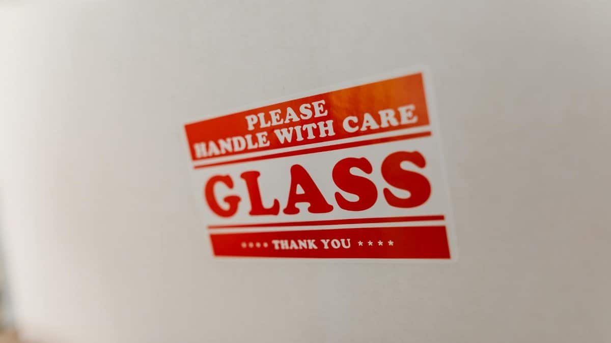 Close-up of a glass packaging label with 'Handle with Care' warning text on a white box.