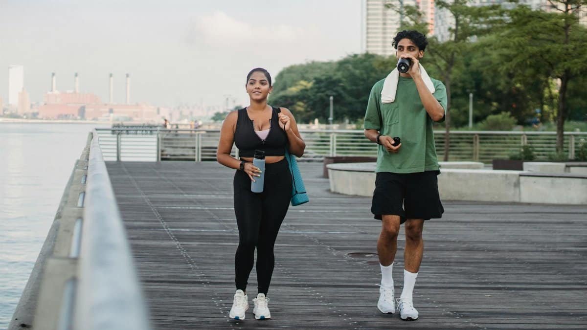 Two friends enjoying a walk on a riverside boardwalk, promoting fitness and a healthy lifestyle.