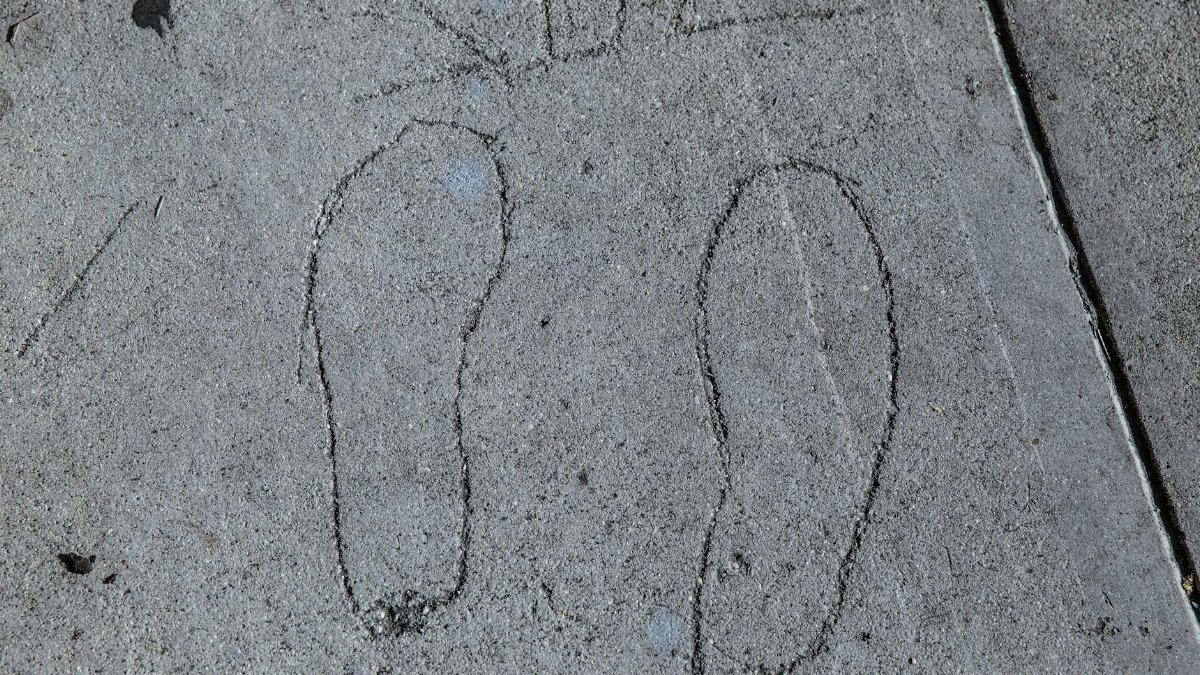 Footprint outlines etched into a concrete sidewalk in Los Angeles.