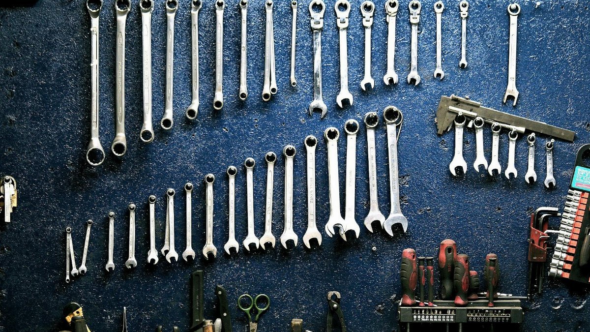 Neatly arranged wrenches and tools on a workshop wall, ideal for mechanics.