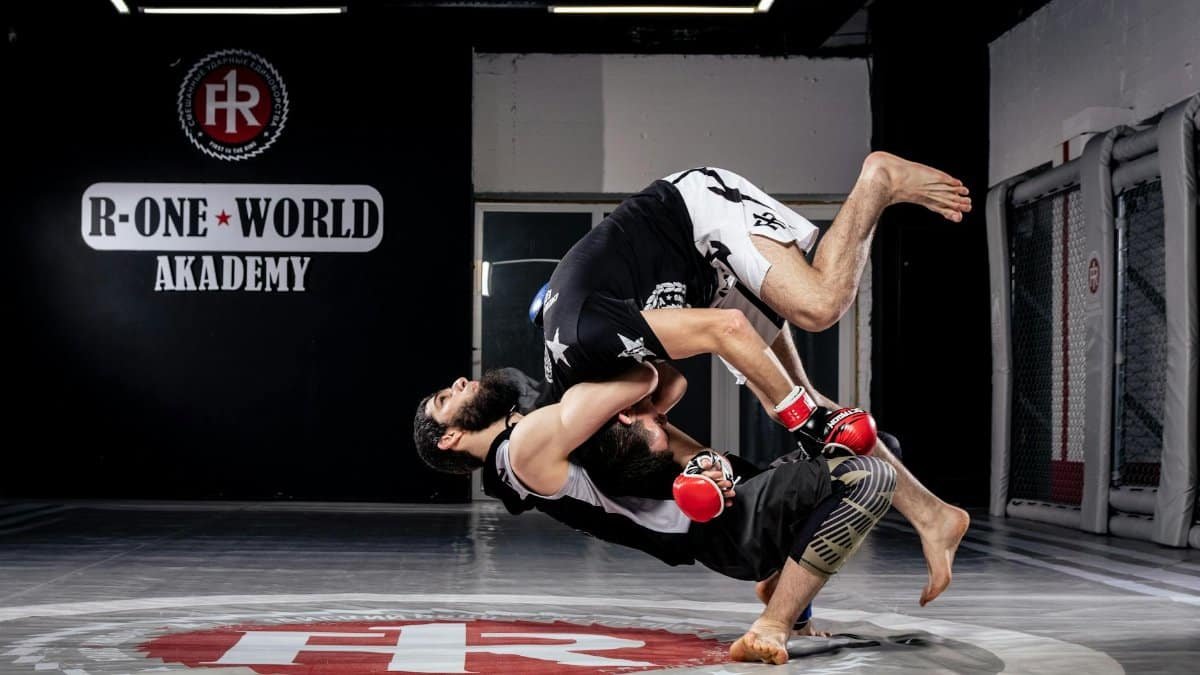 Two martial artists engaged in a high-impact sparring session at R-One World Academy.
