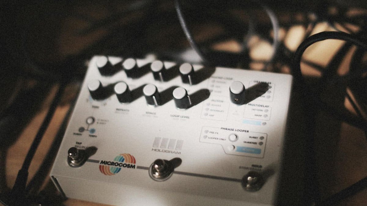 Close-up of audio effects pedal surrounded by cables in a dimly lit music studio, showcasing music technology.