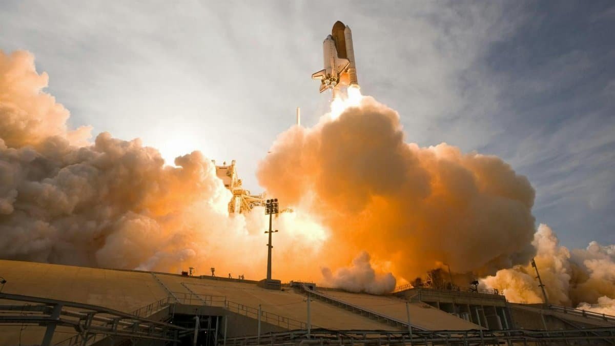 Dramatic view of a space shuttle launching, surrounded by smoke and fire.