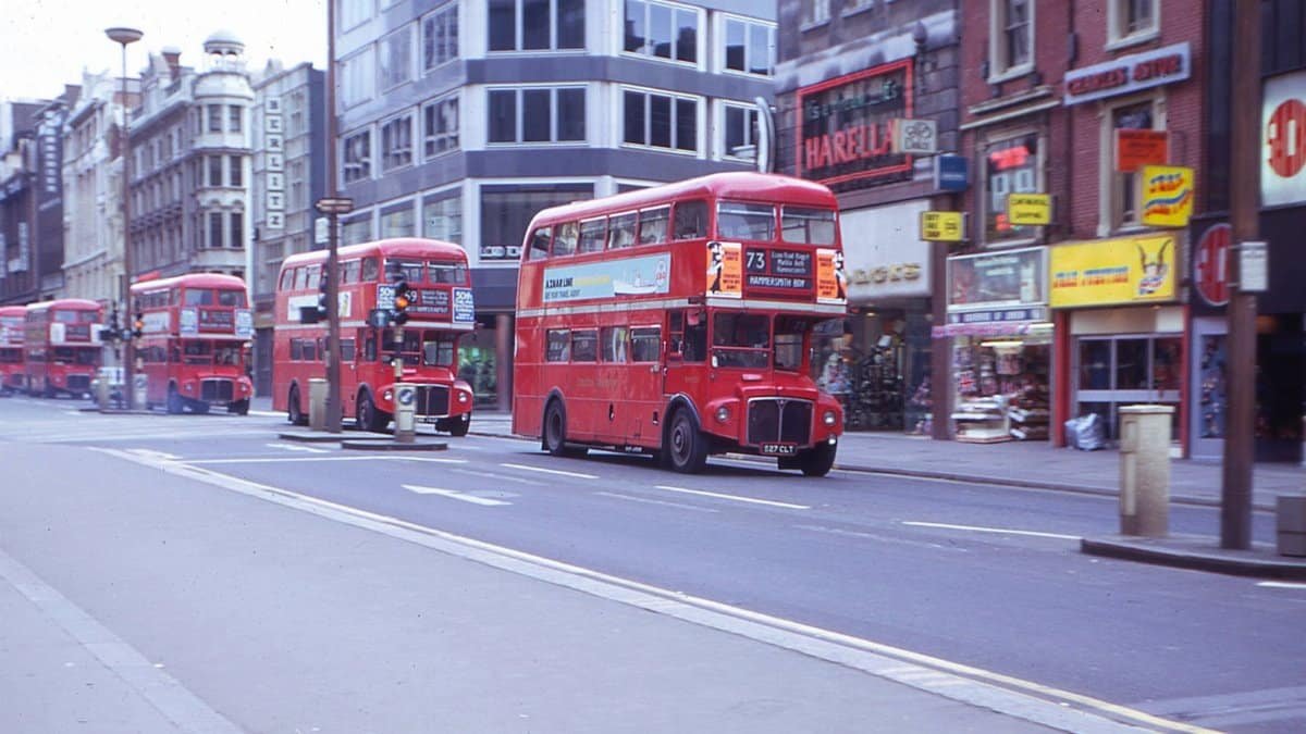 A row of iconic red double-decker buses on a busy city street.