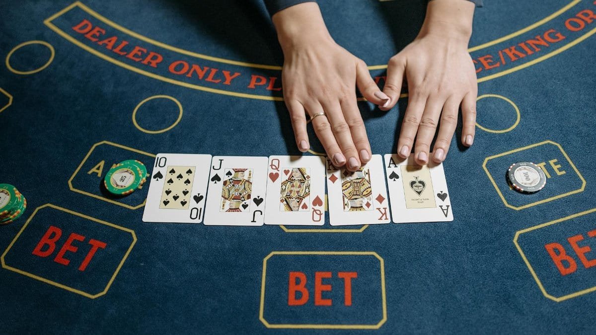 Top view of a casino game with a dealer revealing a winning poker hand on a felt table.