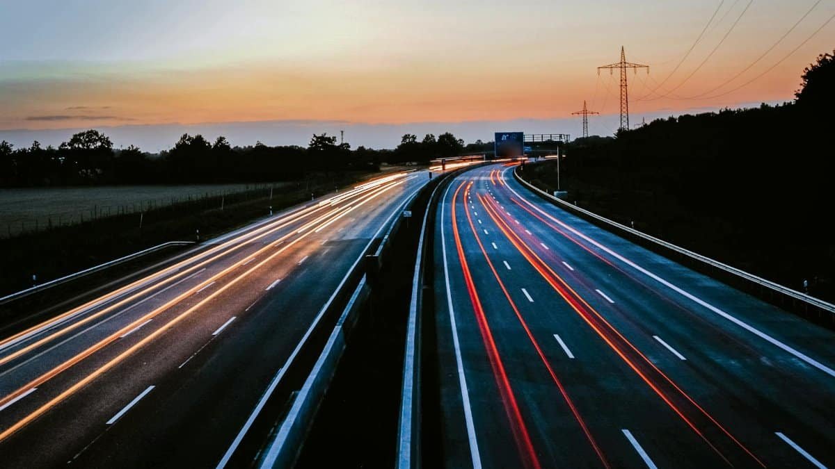 Stunning long exposure of light trails on a highway during dusk, showcasing movement and serene skies.