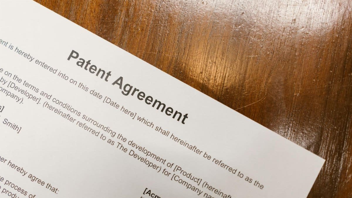 Detailed close-up of a patent agreement document on a polished wooden table.