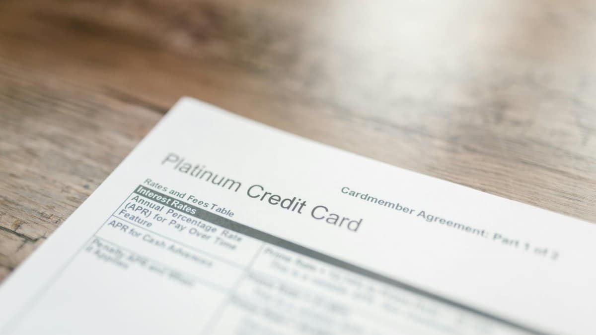 Close-up of a platinum credit card document with interest rates table on a wooden surface.