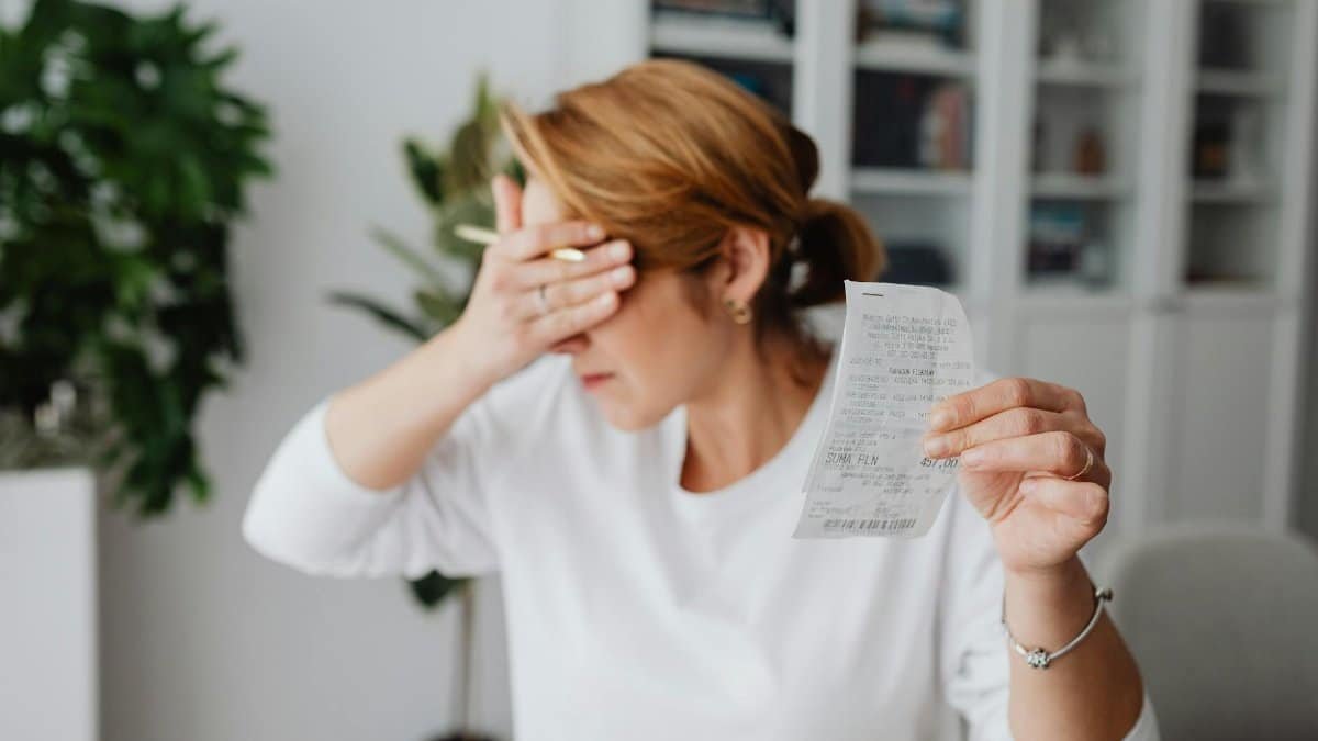 Woman experiencing stress while reviewing household expenses at home.