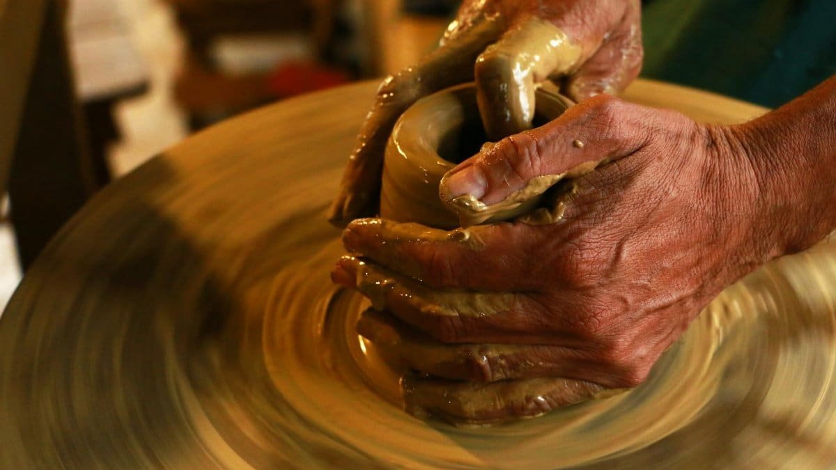 Close-up of hands shaping clay on a pottery wheel, highlighting the art of ceramics.