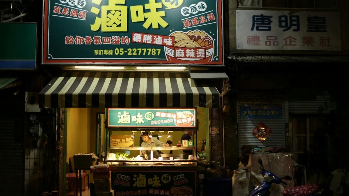 Asian street food stall at night with vibrant signage and busy vendor