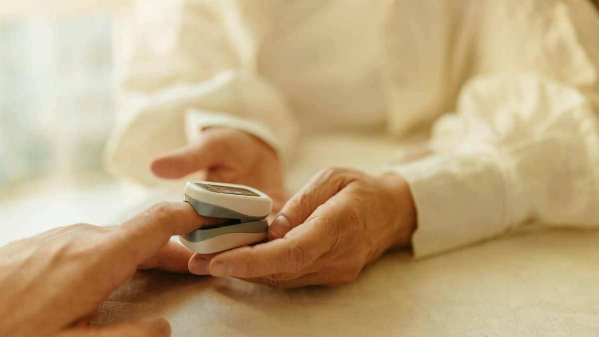 Close-up of a senior adult using a pulse oximeter for a health check indoors.