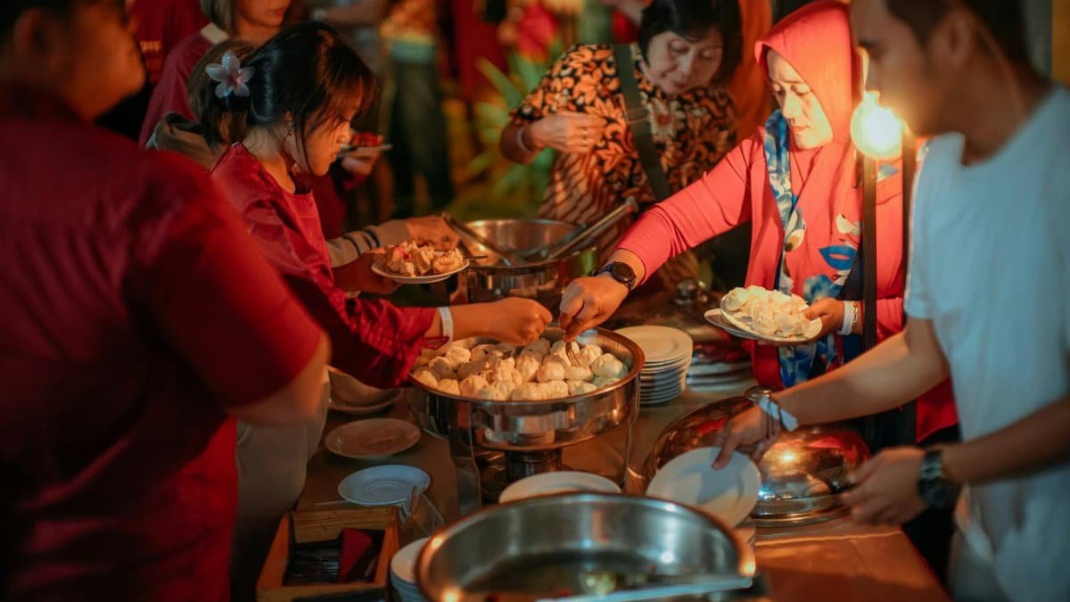 A group of adults engaging in a lively buffet dinner event. Warm lighting and diverse participation.