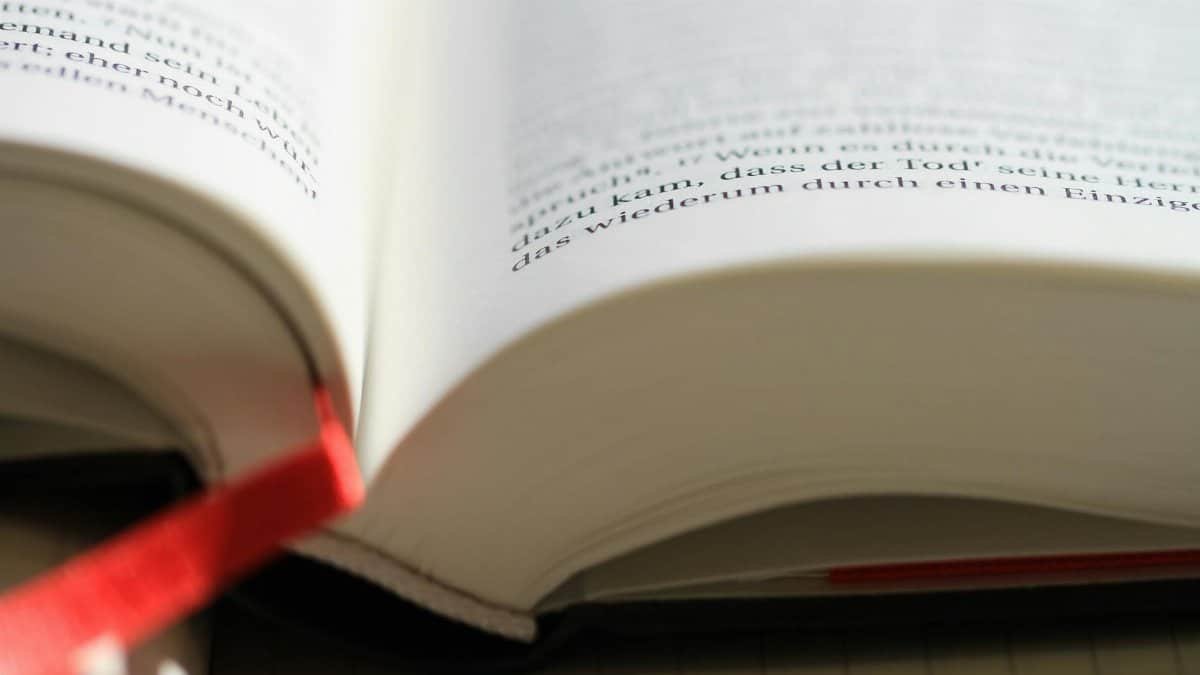 Open book with focus on page and red bookmark for reading and study.