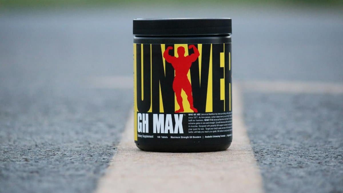 Black container of UNIVERSAL Nutrition GH MAX supplement on a road outdoors.