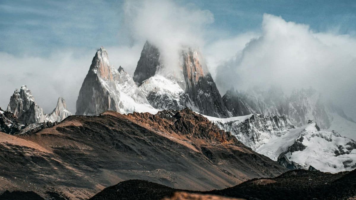 Breathtaking view of Mount Fitz Roy shrouded in clouds, showcasing Patagonia's rugged beauty.