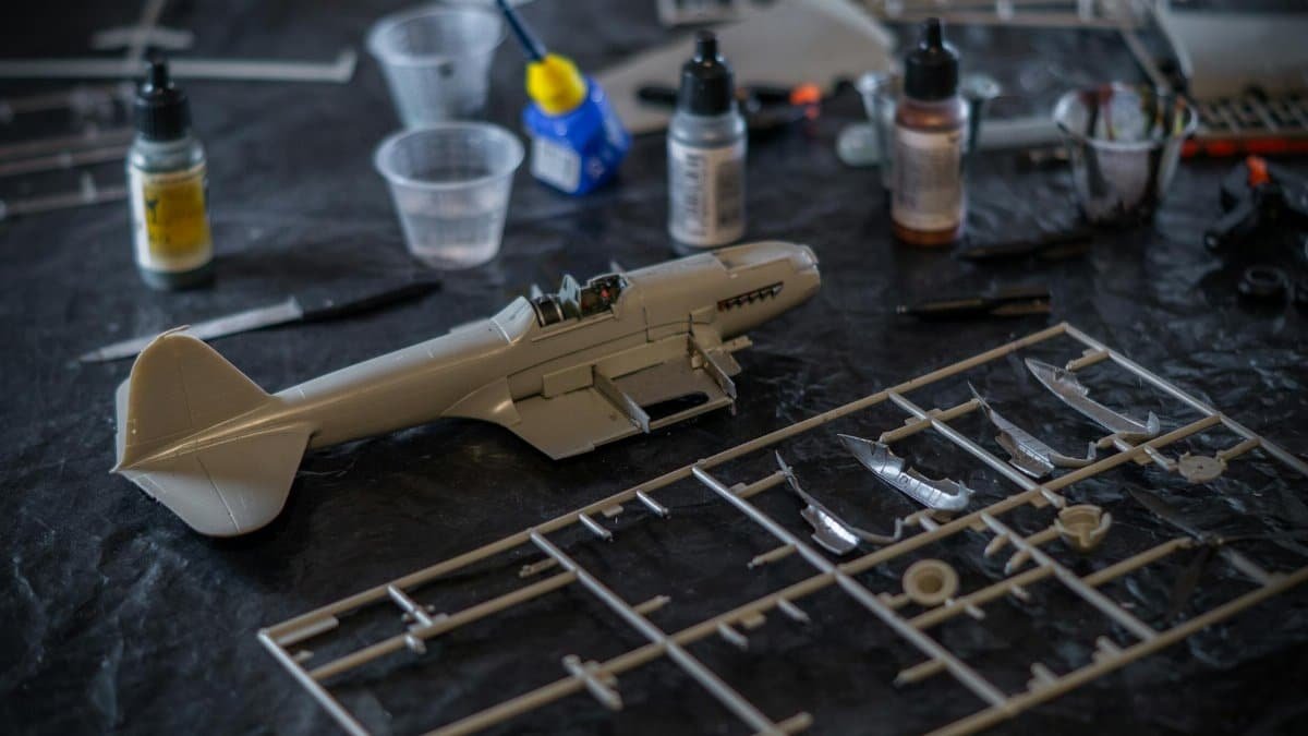 Detailed view of an assembly workspace for a scale model airplane with tools and paint bottles.