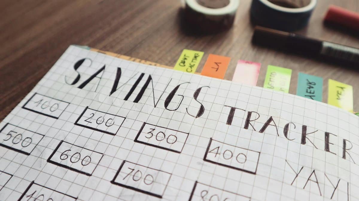 Close-up of a handmade savings tracker with colored tabs on a wooden table, ideal for financial planning visuals.