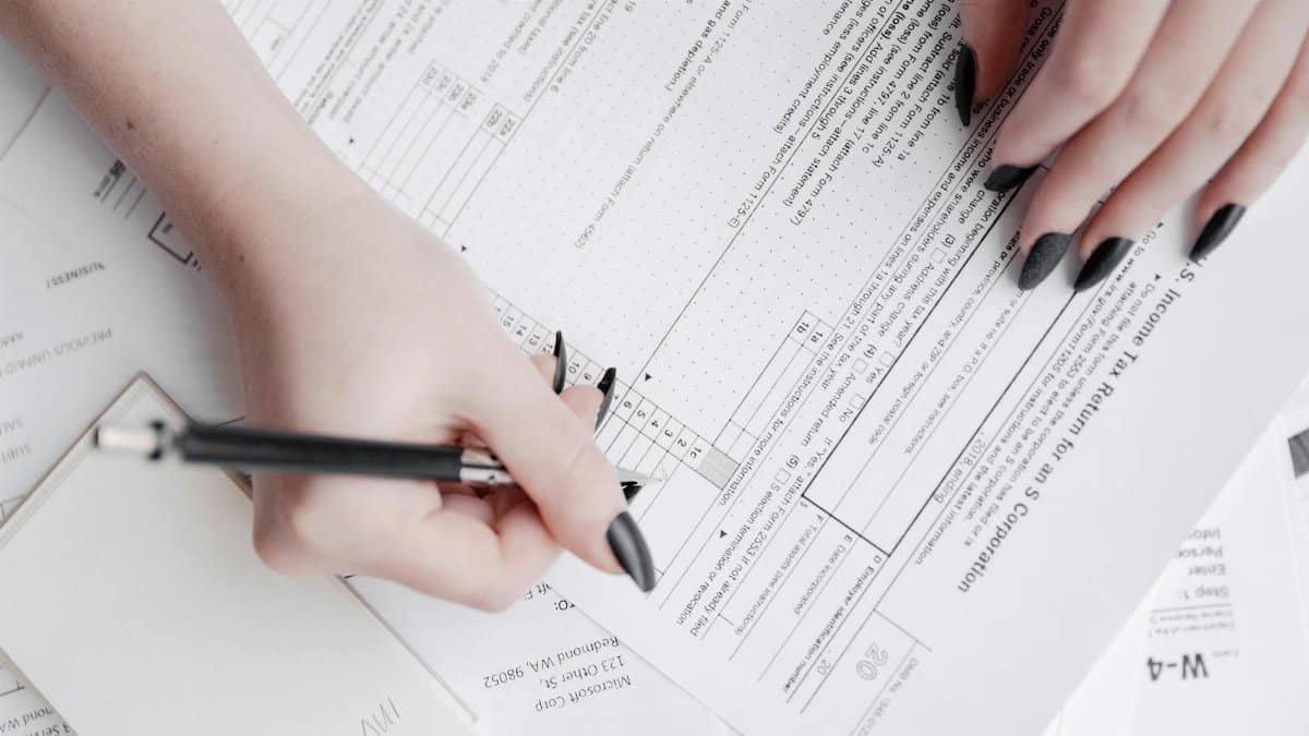 A detailed close-up of a woman filling out tax forms with a pen. Ideal for finance themes.
