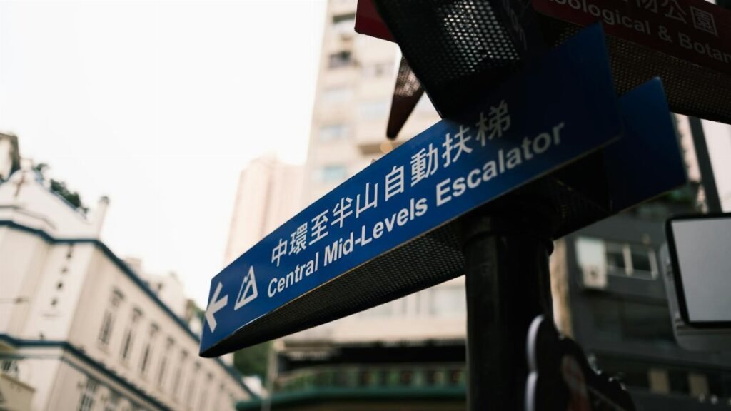 Urban street sign pointing to Central Mid-Levels Escalator in Hong Kong.