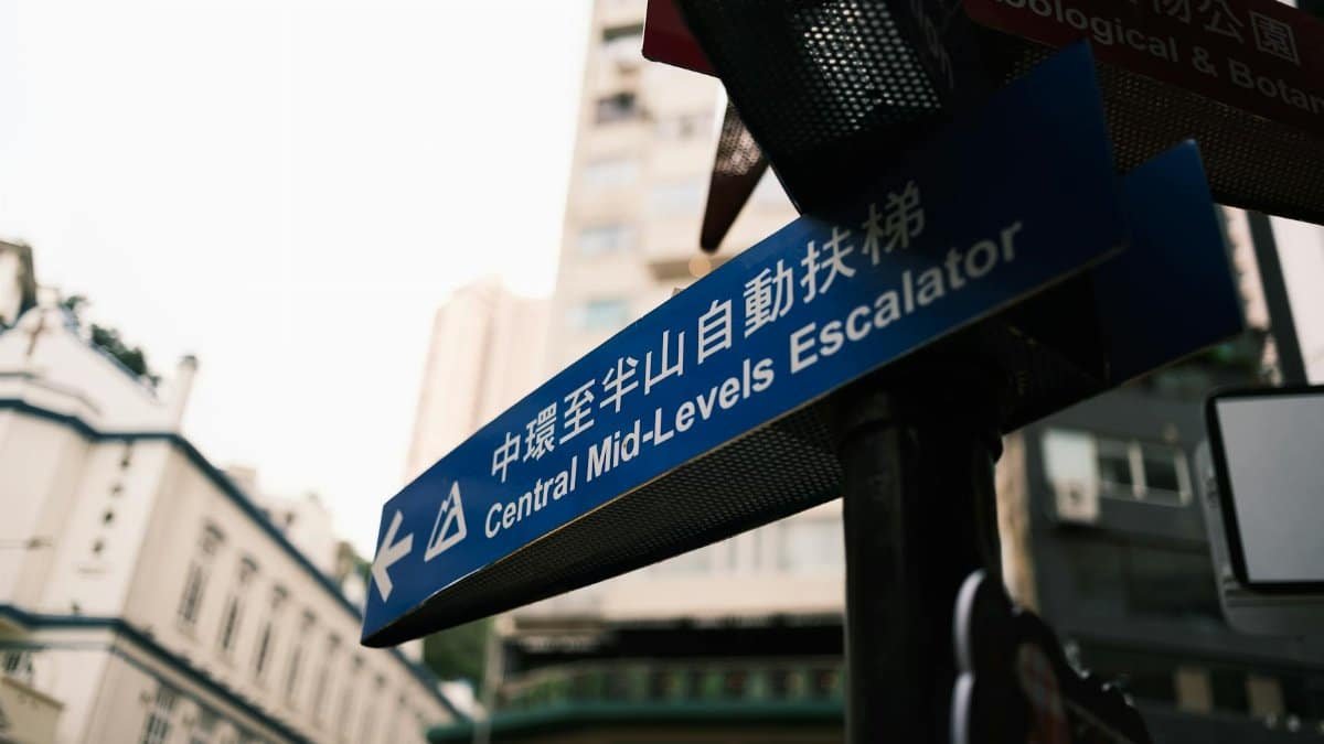 Urban street sign pointing to Central Mid-Levels Escalator in Hong Kong.