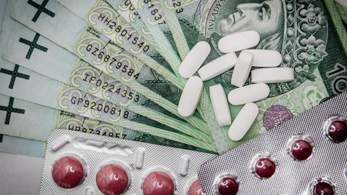 Polish 100 złoty notes with pills and blister packs, illustrating medical costs.