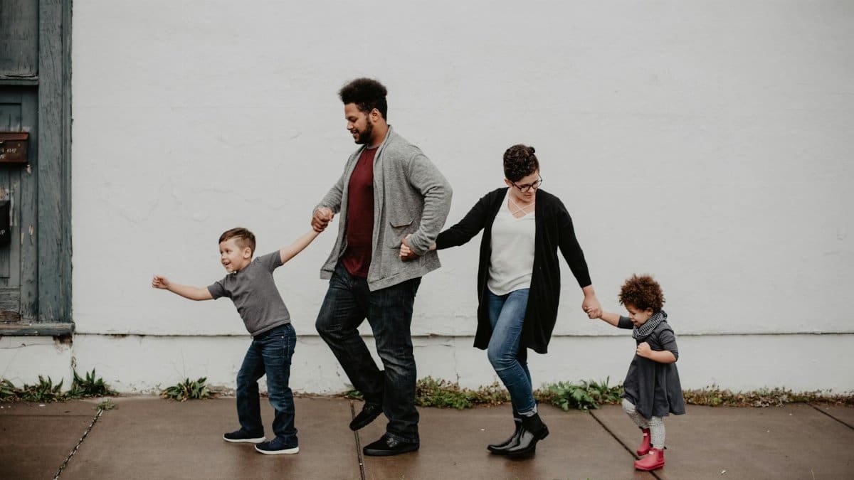 A joyful family walking together outdoors, holding hands in a playful and happy moment.