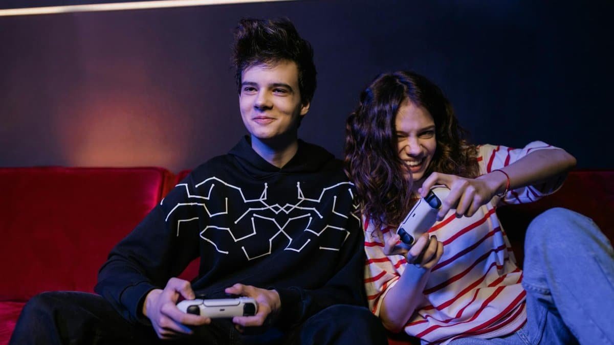 Two teenagers playing video games together, smiling and enjoying the moment indoors.