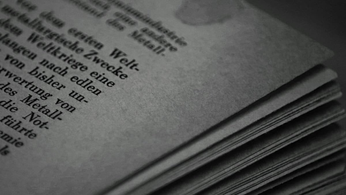 Monochrome close-up of book pages with German text, showcasing texture and typography.
