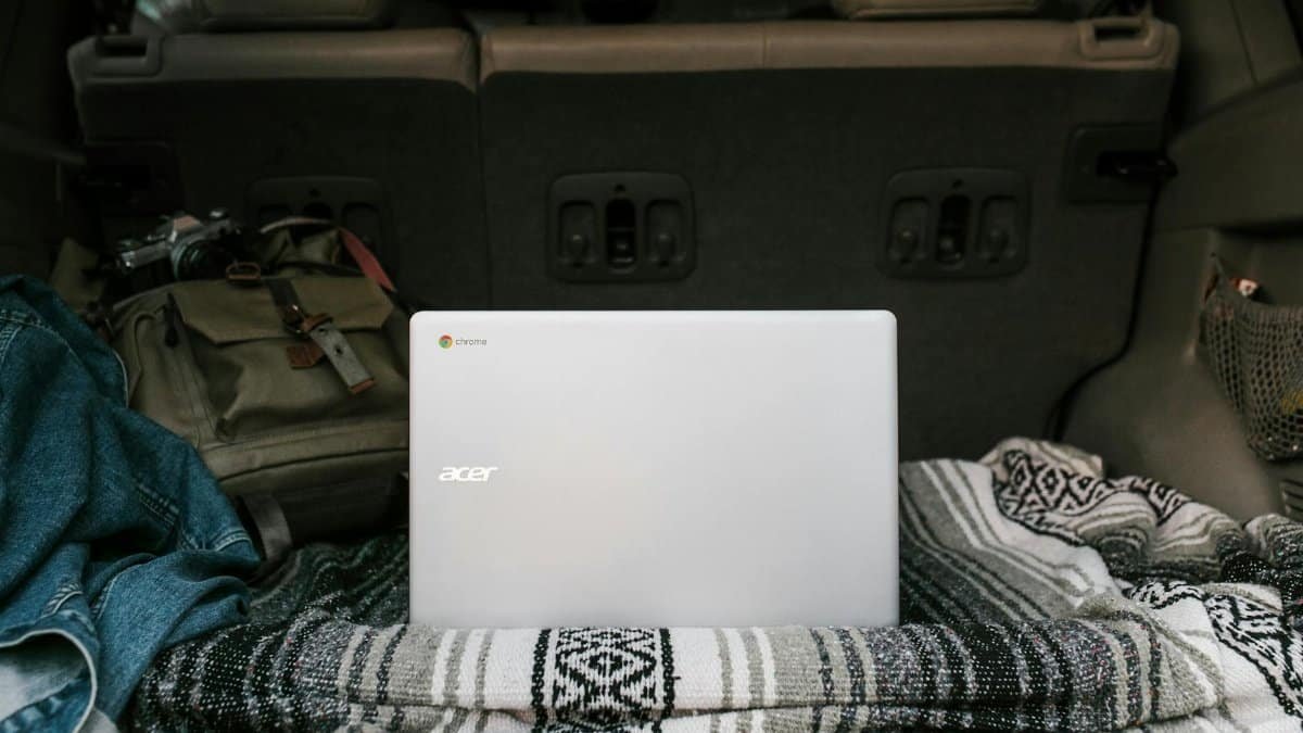Laptop setup in a car trunk with cozy blanket for remote work travel ease.