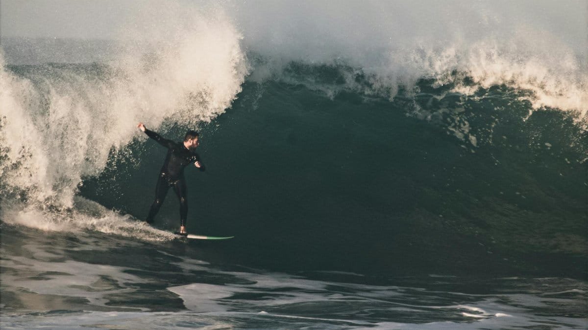 A dynamic shot of a surfer skillfully maneuvering a towering ocean wave, capturing pure adrenaline.