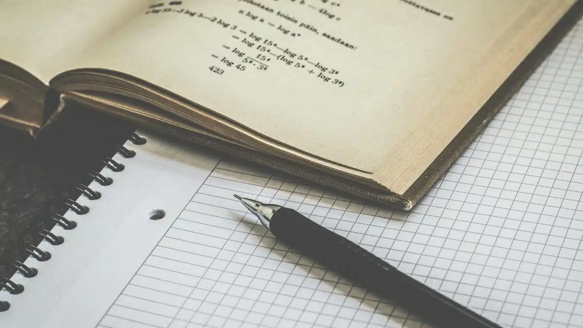 Mathematical study scene with open book, graph paper, and pen for learning and homework.