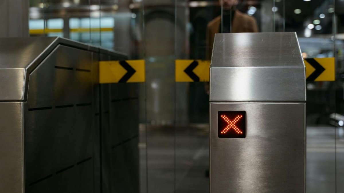 Close-up of a stainless steel ticket barrier with red X signal indicating no entry.