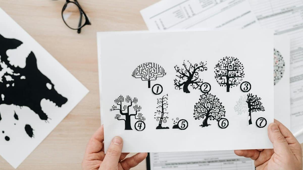 Close-up showing hands holding paper with tree test illustration for psychological assessment.