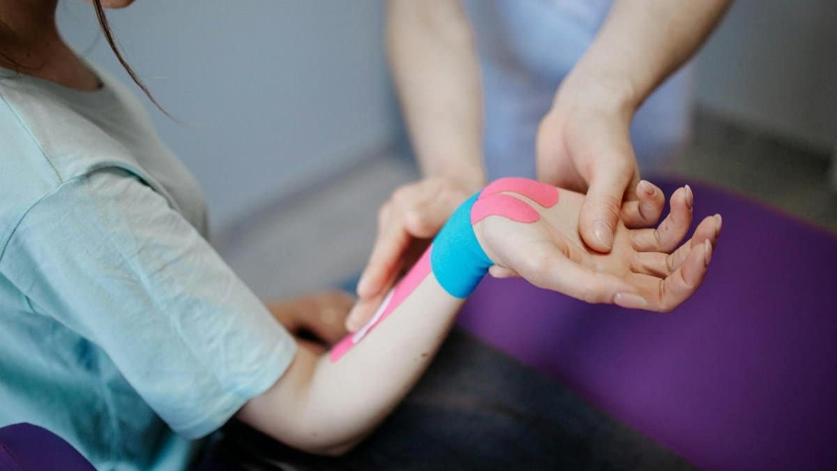 Close-up of a therapist applying kinesio tape for pain relief during a therapy session.