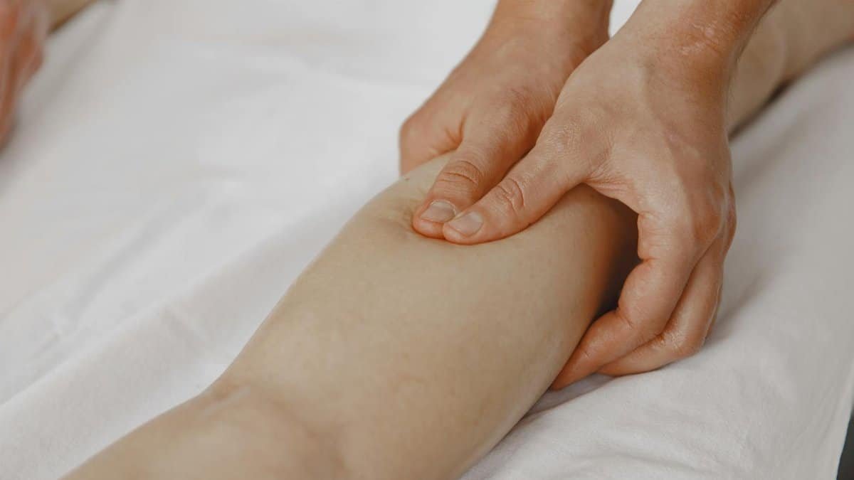 Close-up image of a massage therapist applying pressure on a client's leg for muscle relaxation.