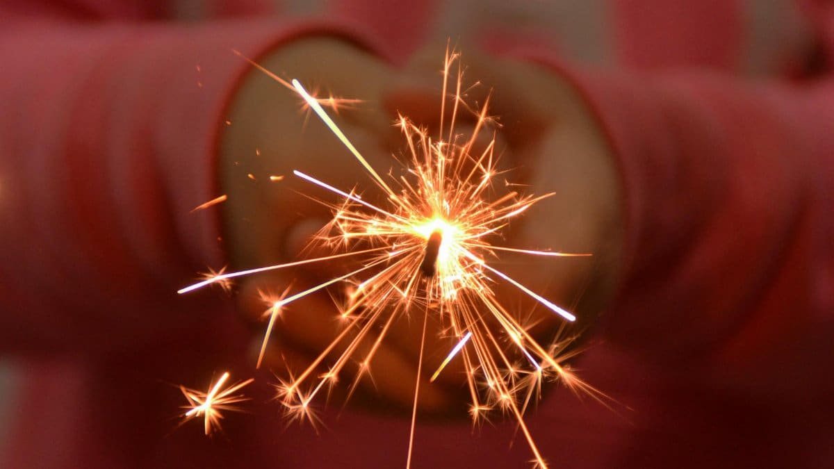 Close-up of a child holding a glowing sparkler, symbolizing joy and festivity.