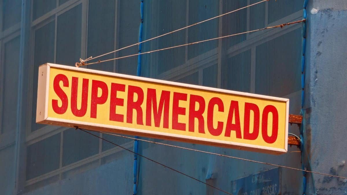 Close-up of a vibrant supermercado sign hanging outdoors in Las Palmas, Spain.