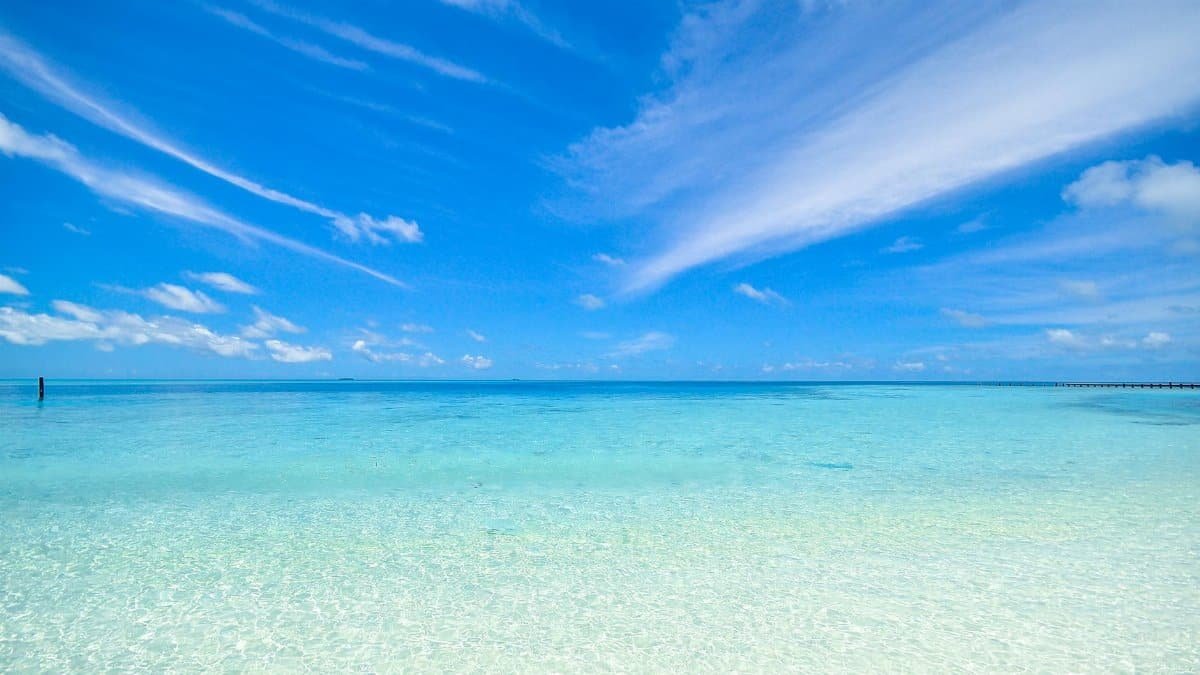 Experience the tranquil turquoise waters and clear sky at Laamu Atoll, Maldives. Perfect for a relaxing getaway.