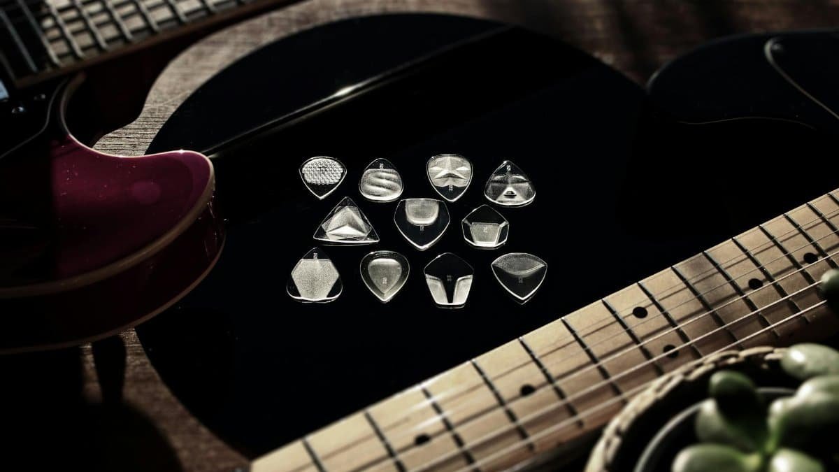 Beautifully arranged image featuring electric guitars and transparent guitar picks on a dark surface, illuminated by natural light.
