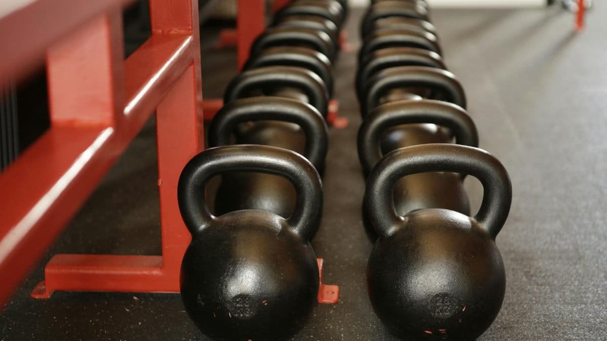 Black kettlebells lined up in a gym, ready for fitness training.