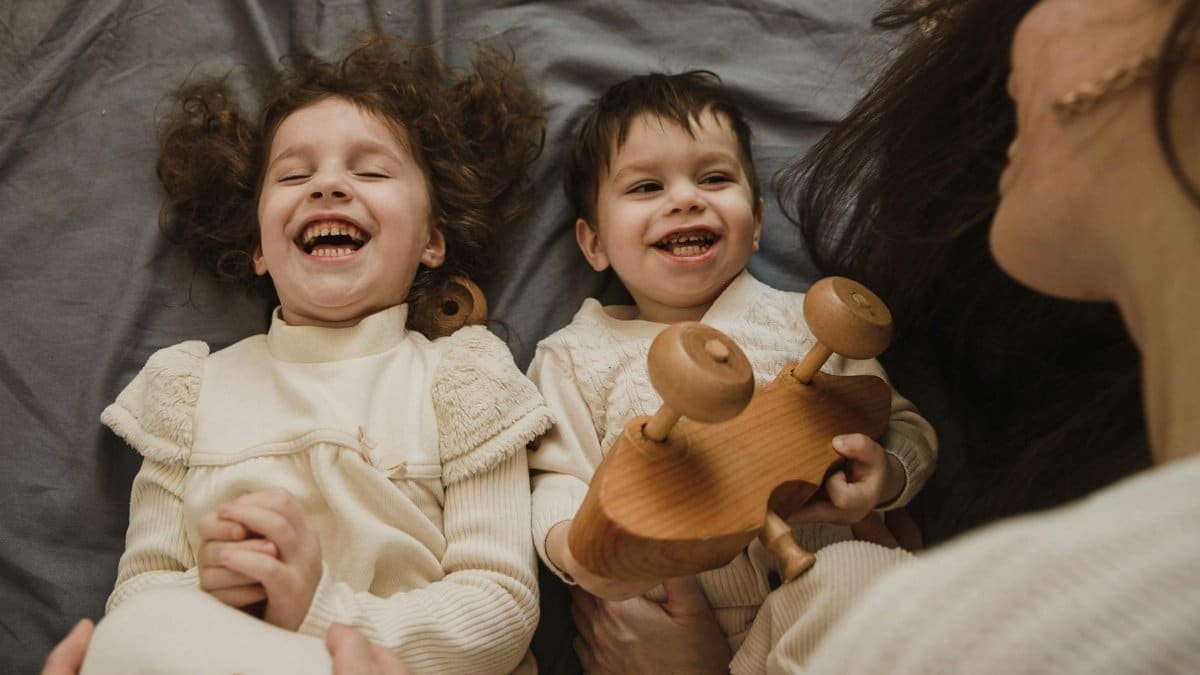 Happy family bonding time featuring a mother and her children enjoying a playful moment together indoors.