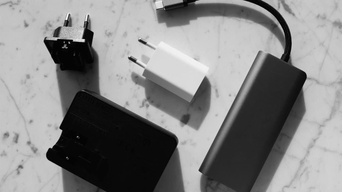 Flat lay of various electronic chargers on a marble surface with strong shadows.