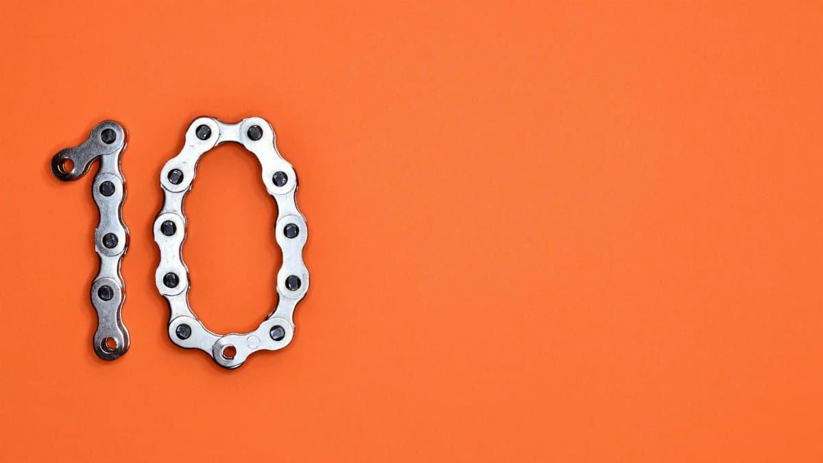 Bicycle chain arranged to form the number ten against a bright orange background.