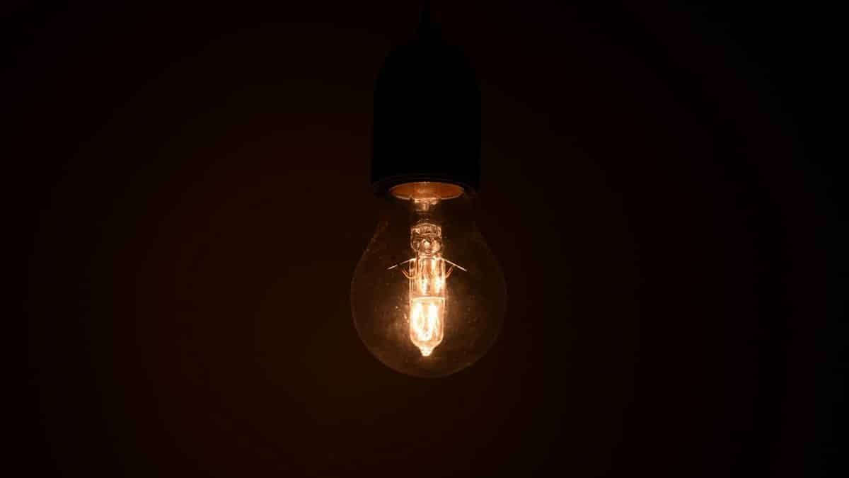 Close-up view of an illuminated light bulb glowing in a dark environment, emitting warm light.