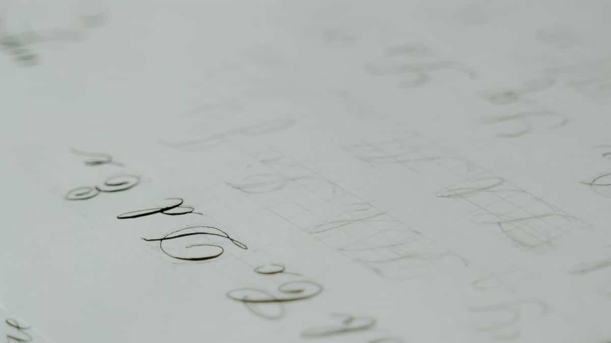 Close-up of a calligraphy practice sheet with elegant cursive lettering on white paper.