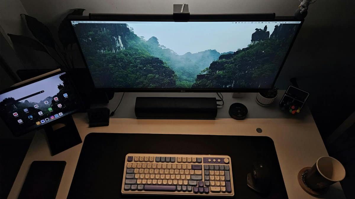 Modern home office desk with keyboard, widescreen monitor, and tablet, creating an ideal productivity setup.