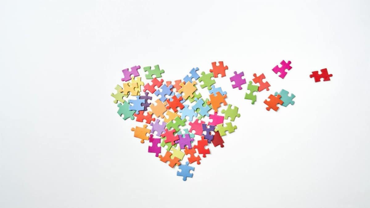 Vibrant puzzle pieces form a heart shape on a plain white background.